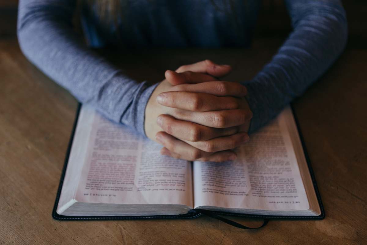 prayer man holding his hands on open book faith