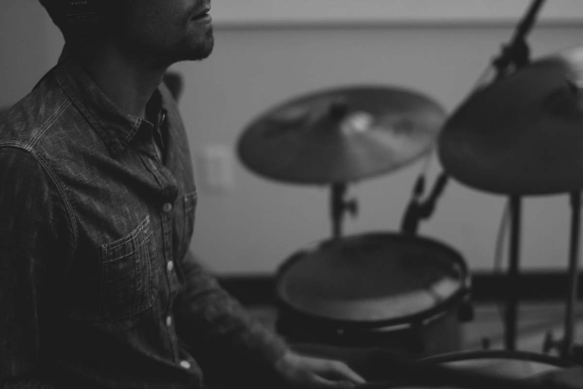 drummer grayscale photo of man playing drum musical instrument