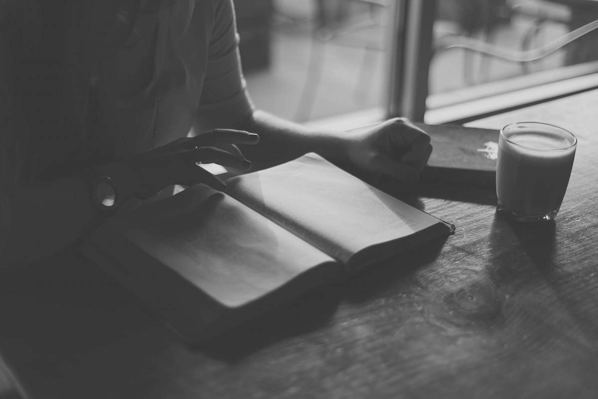 grey grayscale photo of person reading book drink