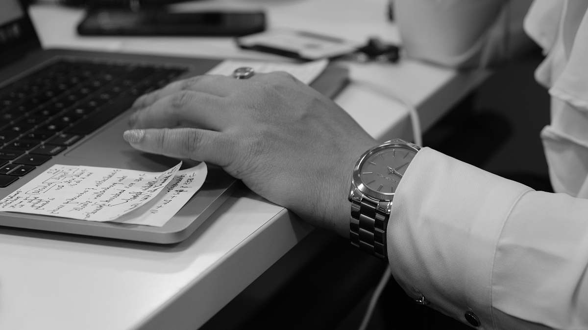 wristwatch grayscale photo of person's hand on laptop computer keyboard