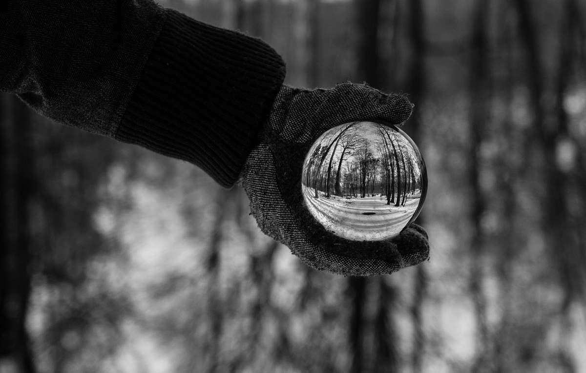 winter person holding clear crystal ball grayscale photography glove