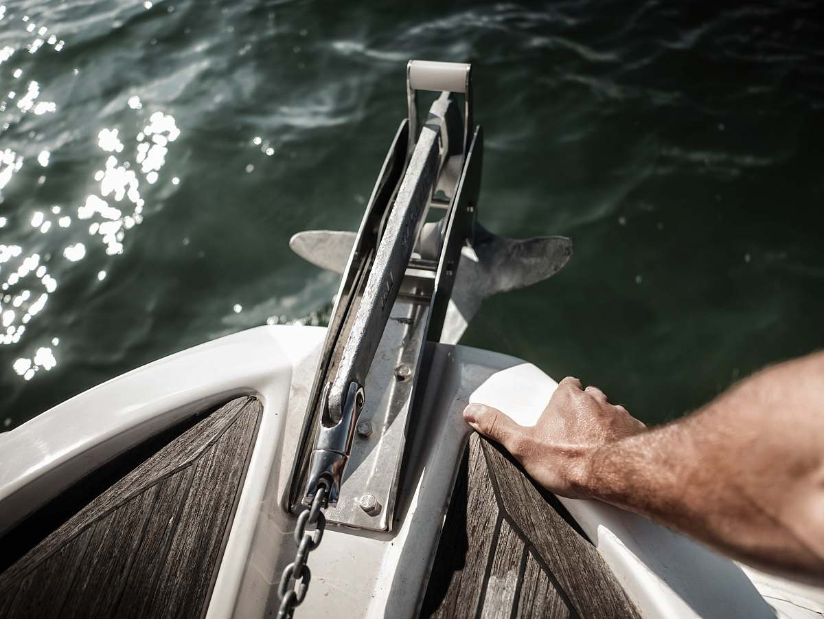 arm person holding the edge of the boat near anchor chain