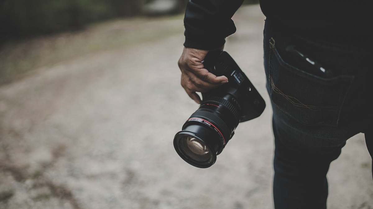 grey person holding DSLR camera lens