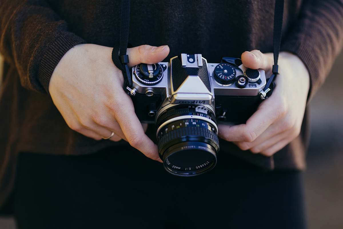 human person holding gray and black SSLR camera person
