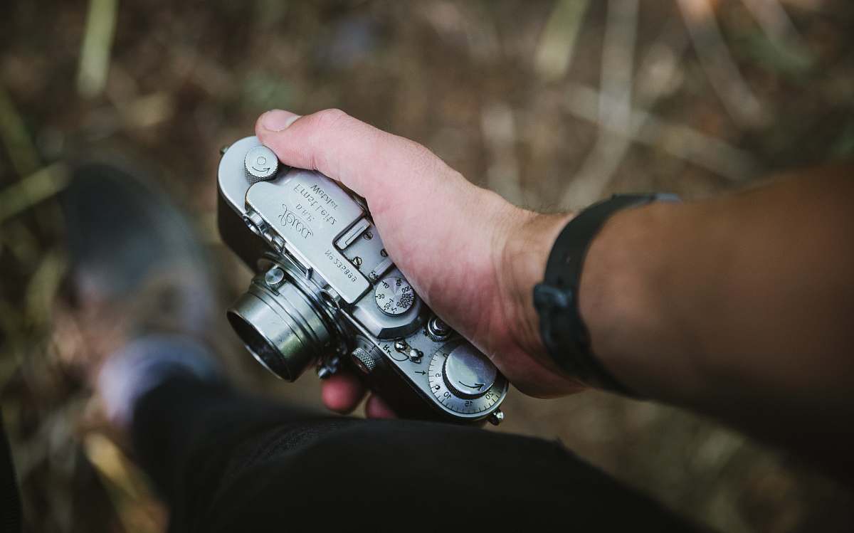 photography person holding silver point-and-shoot camera vintage