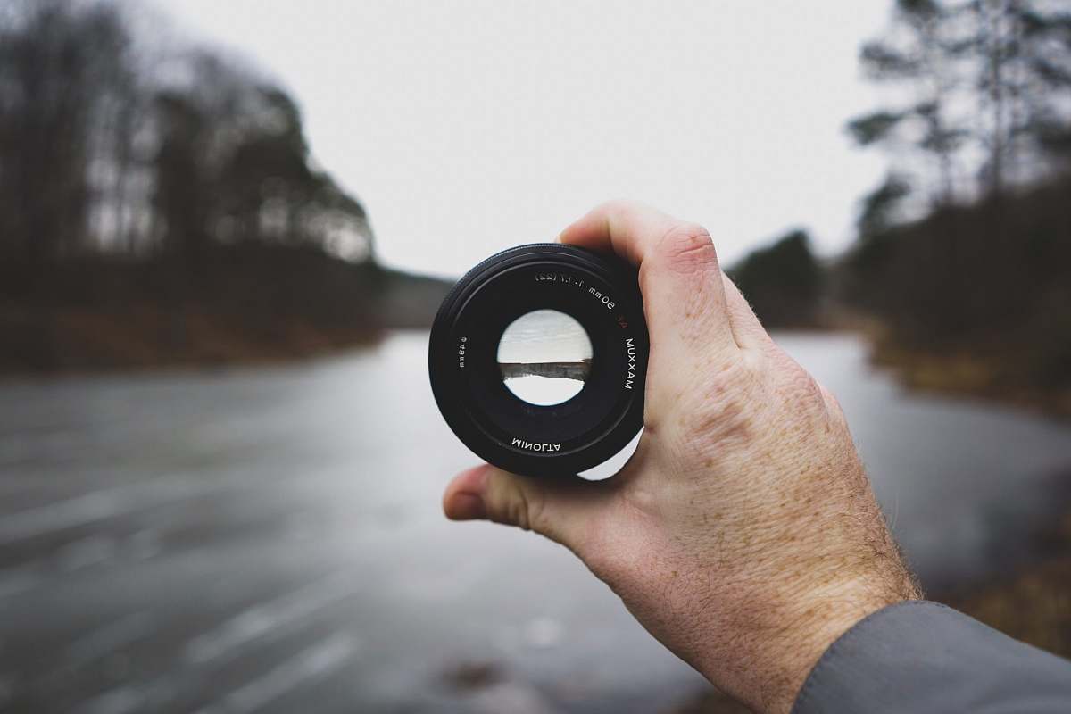 focus selective focus photo of person's hand holding black camera lens blur