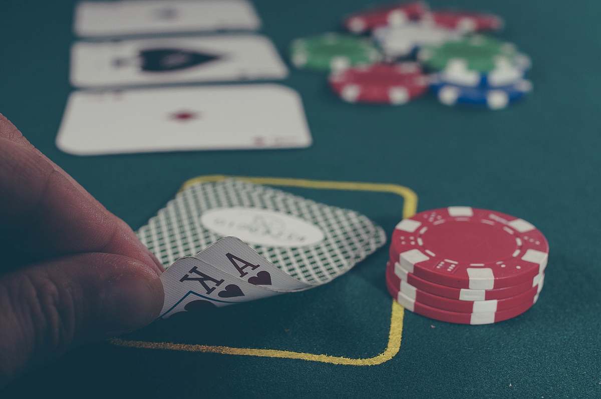 gambling person holding black ace and king spades playing cards on poker table game