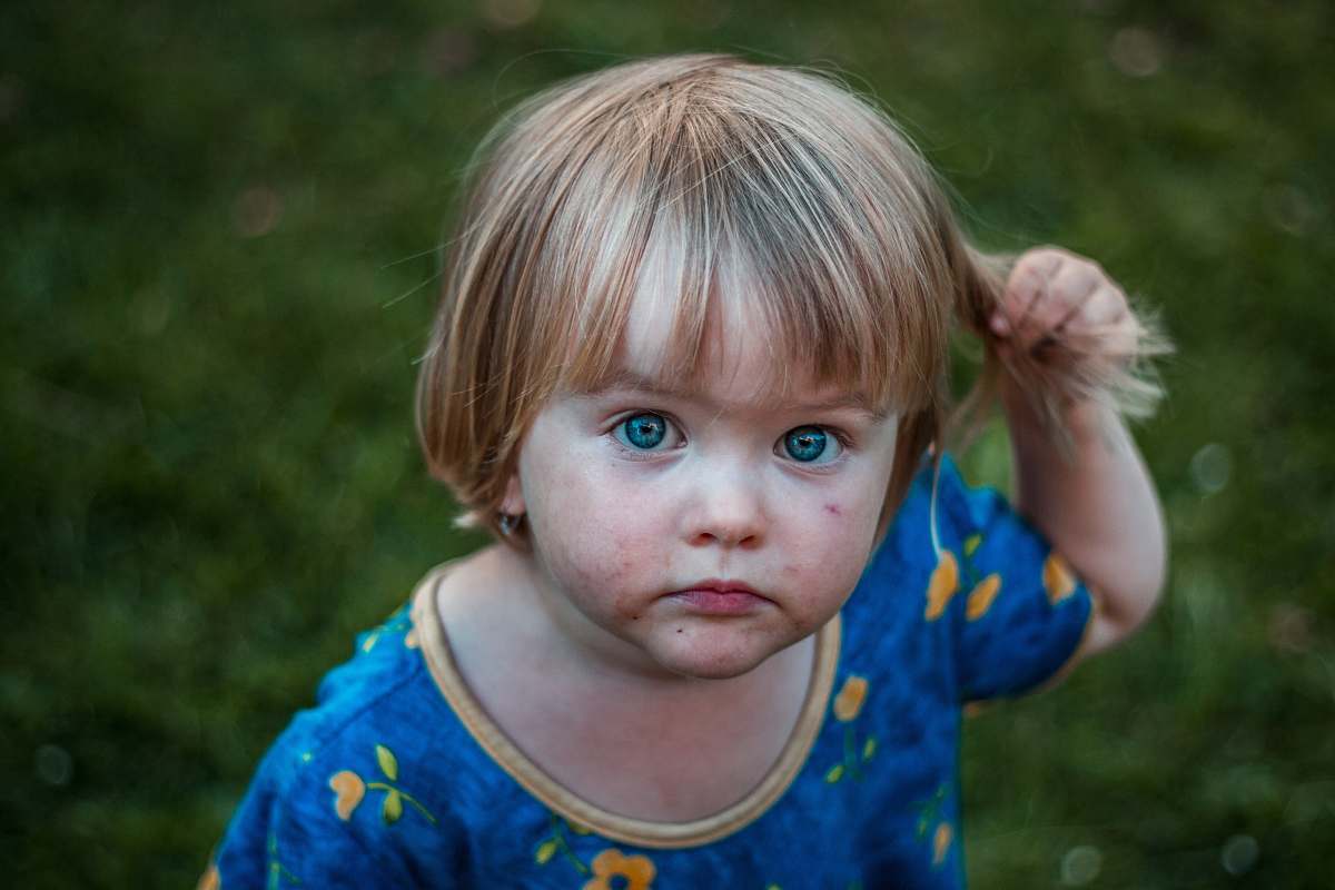 childhood selective focus photography of girl holding her hair toddler