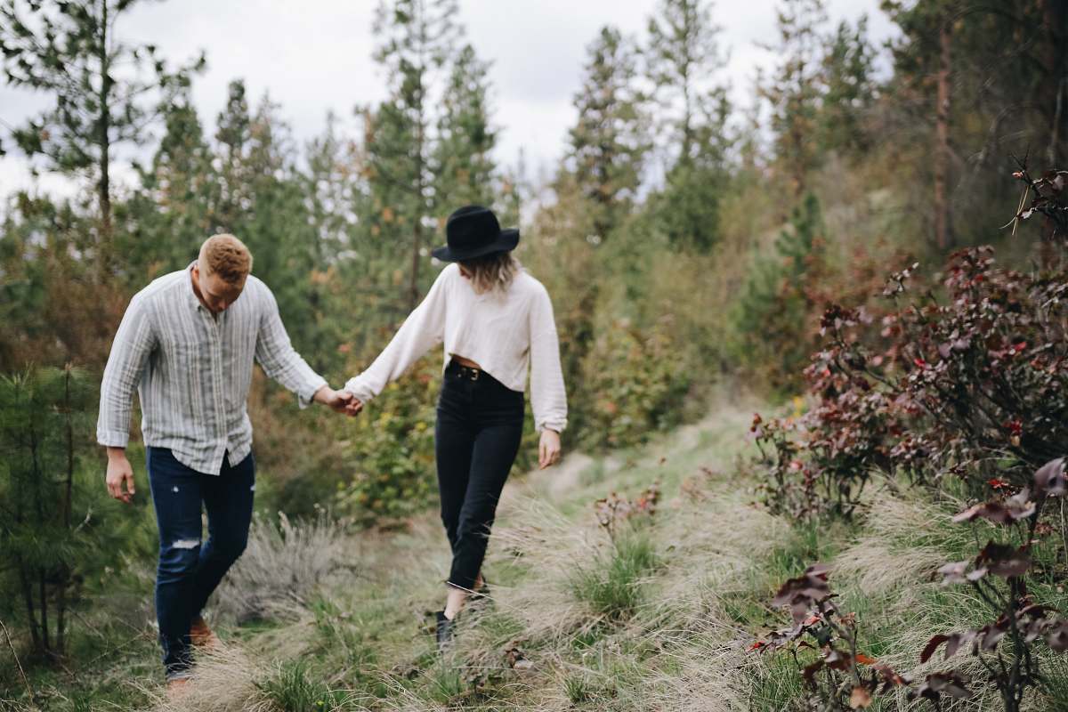 human man and woman holding hands walking beside trees person