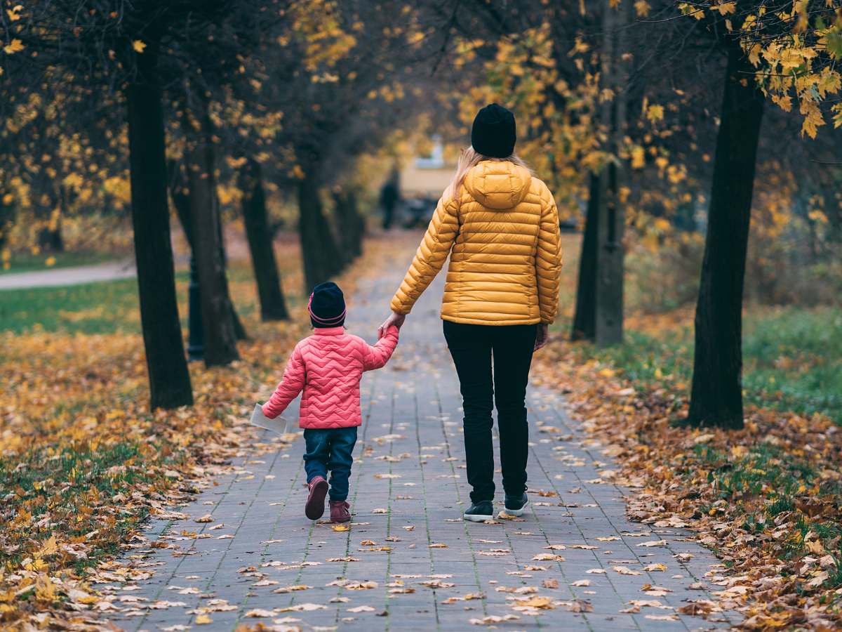 apparel person holding child walking on pathway footwear