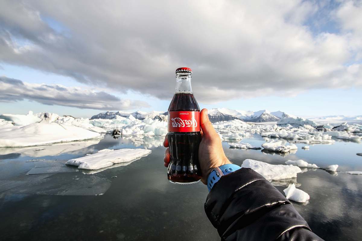 bottle person showing photo of bottle of coke in front of icebergs beverage