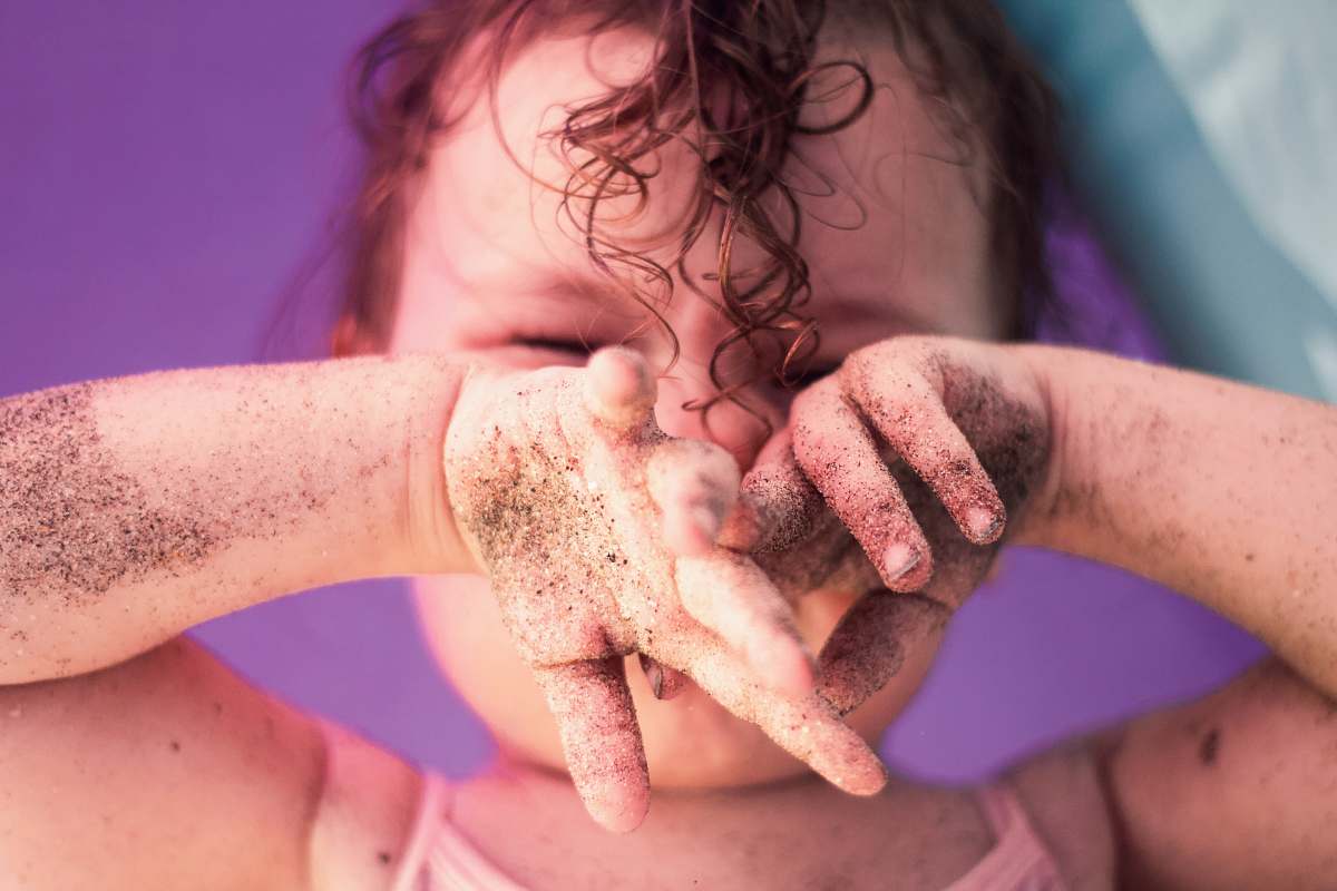 human baby with black sand on hand person