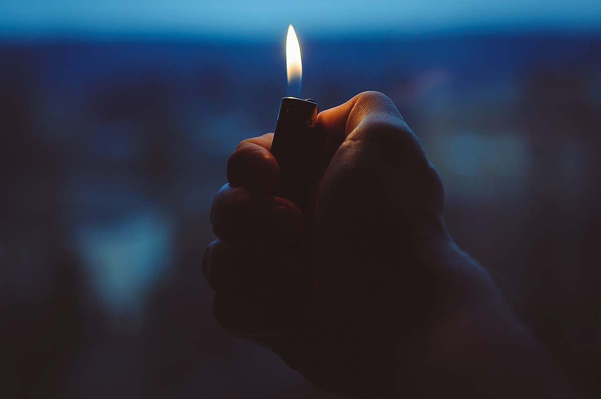 flame person holding black lighter lighter