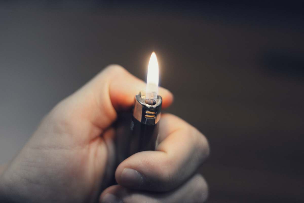 fire person holding black lighter lighter