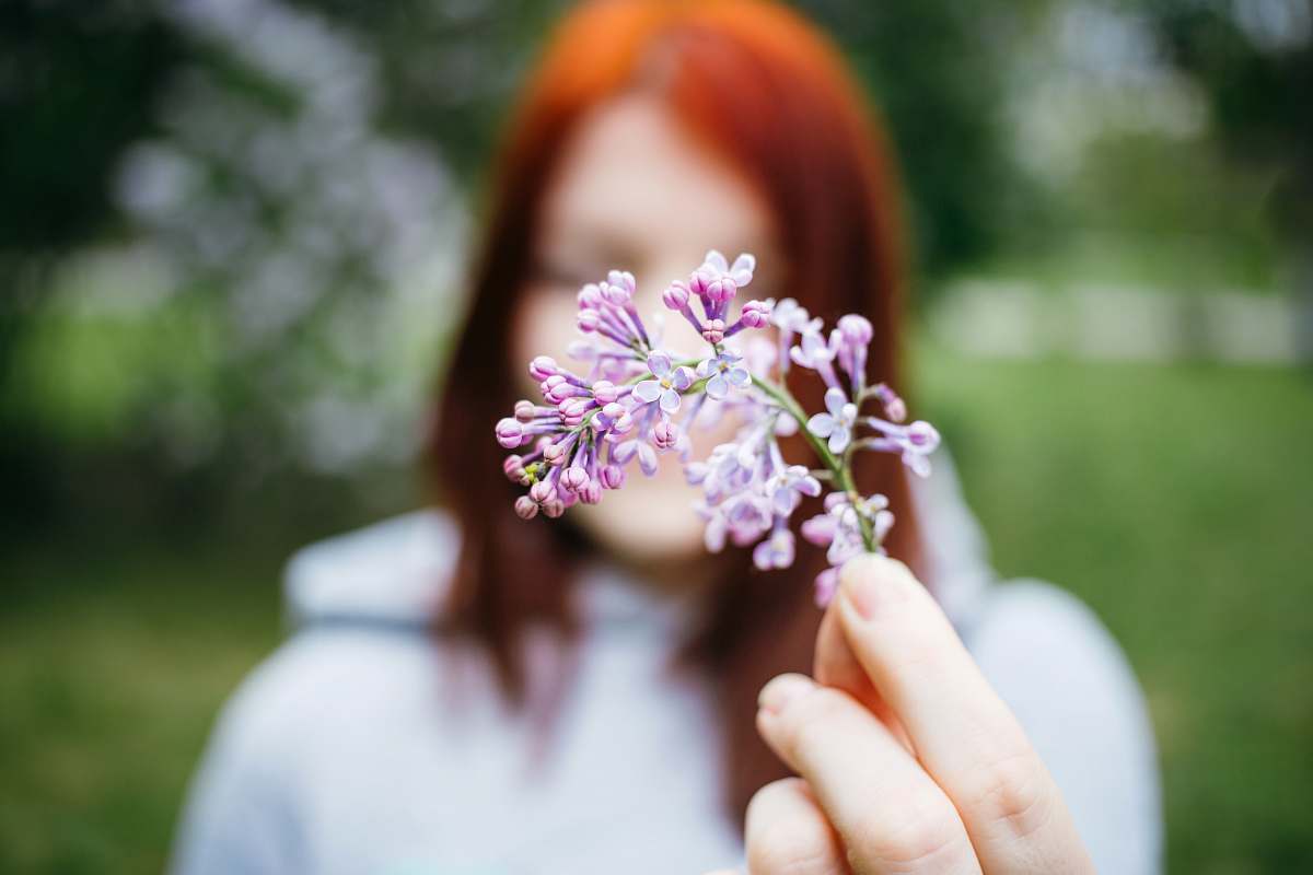 blossom macro shot photo of woman holding purple flower standing outside moscow