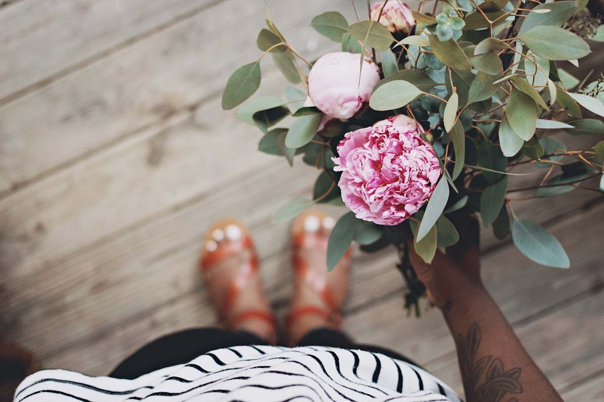 woman person holding pink flowers standing on brown wooden flooring green