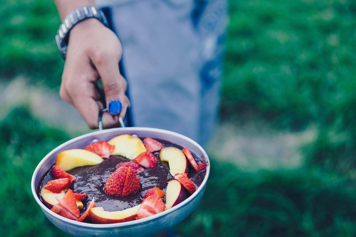 hand person holding pan filled with sliced strawberries pan
