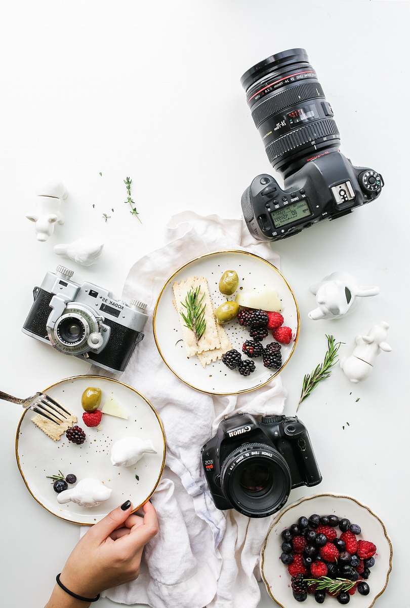 camera three assorted cameras near fruits and ceramic figurines food