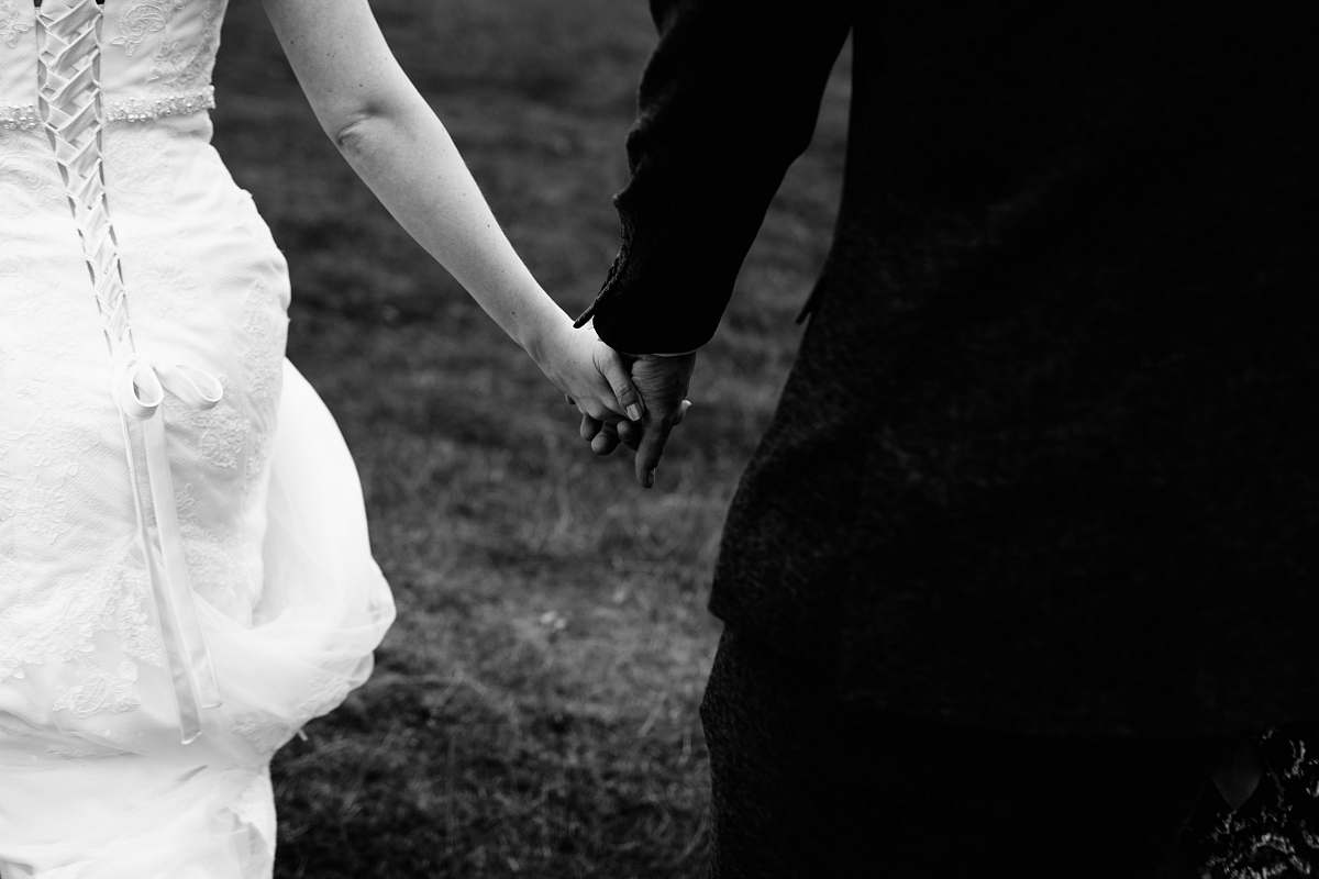 black-and-white bride and groom holding hands together holding hands