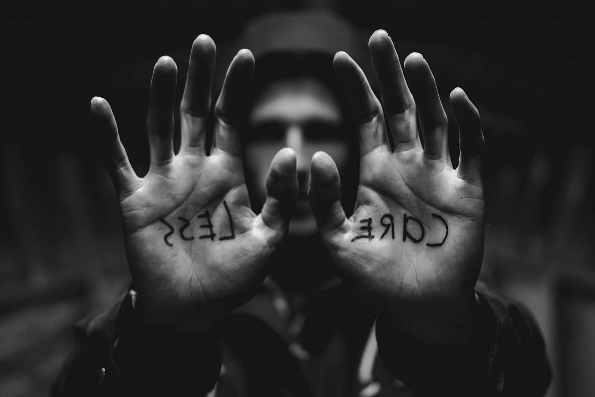black-and-white gray scale photography of man raising both hands with care less text on palm grey