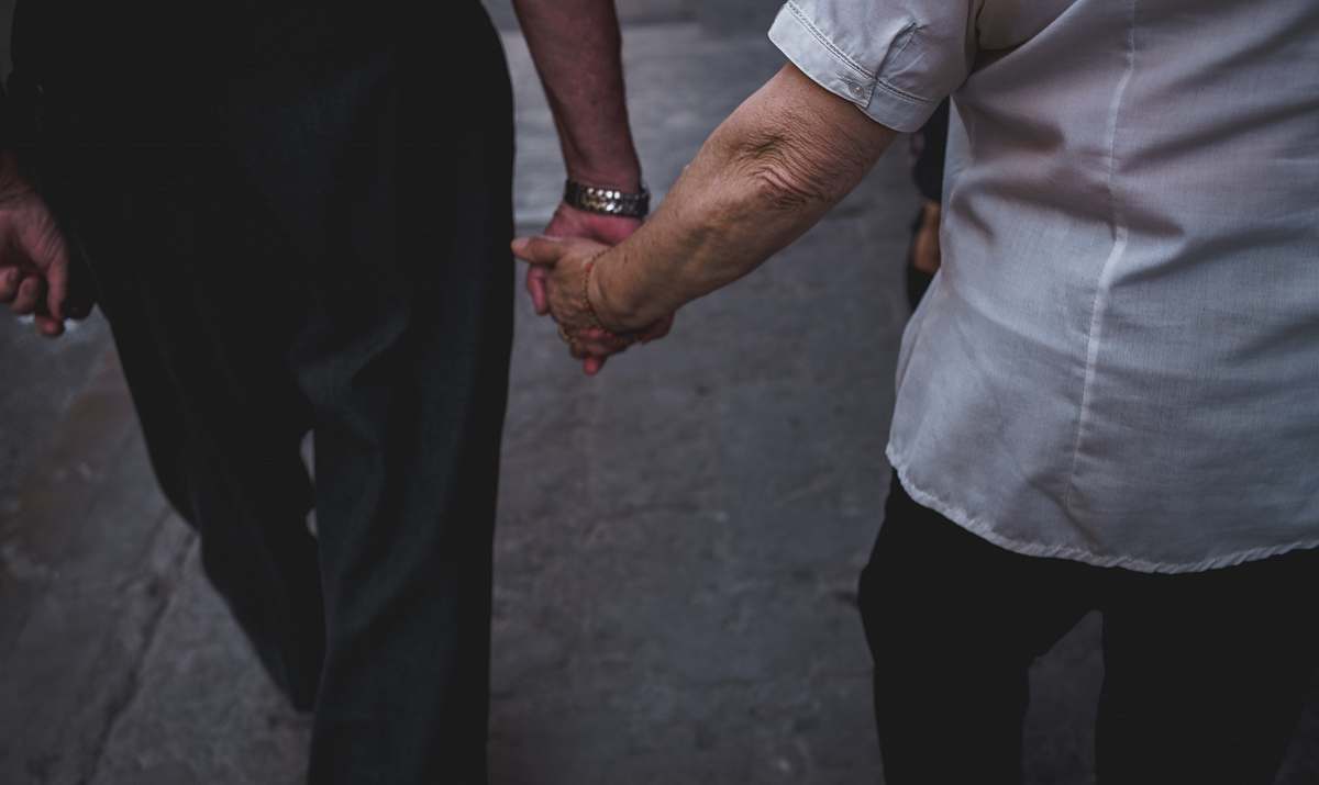 human man and woman holding hands while walking during daytime holding hands