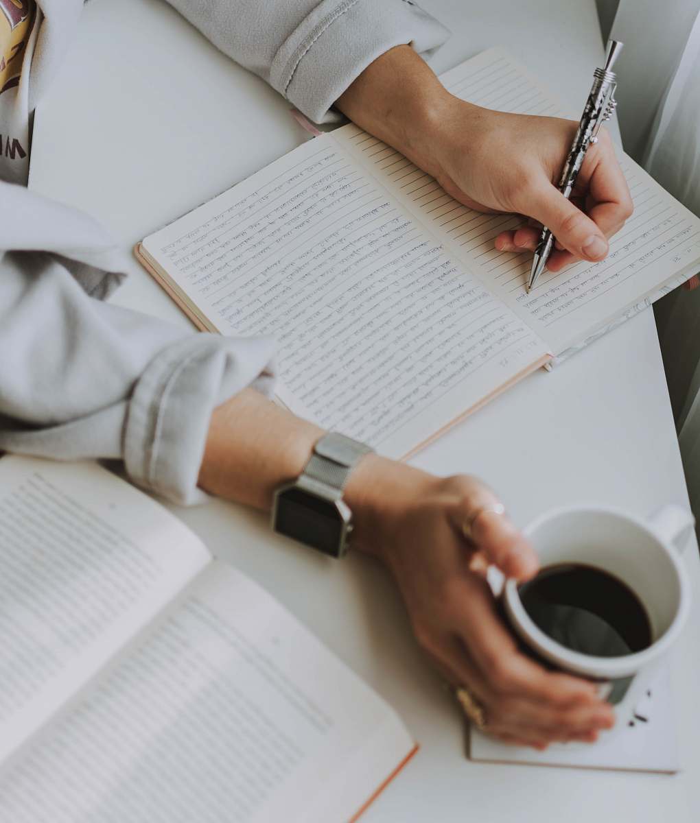 text man writing while holding mug diary