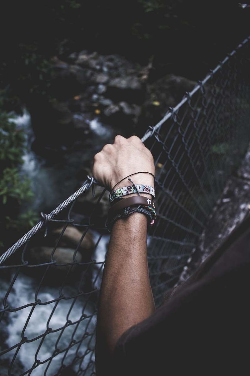 river person crossing hanging bridge wrsitband