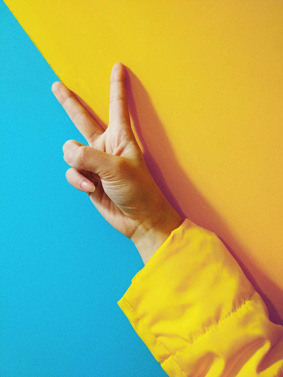 yellow person doing peace hand sign blue