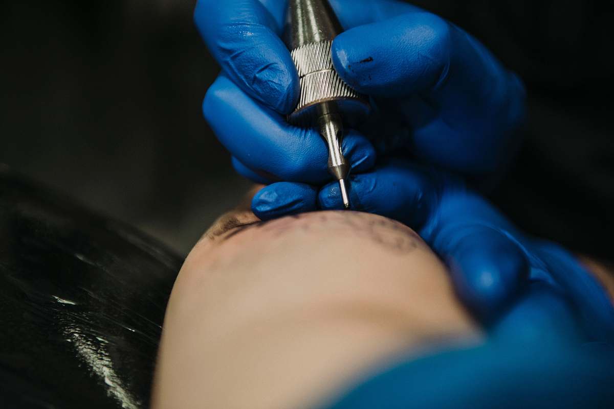 injection person doing tattoo in closeup photo finger