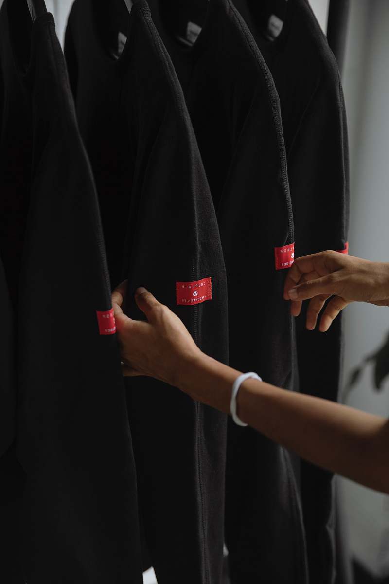 arm person holding black jackets inside room clothing