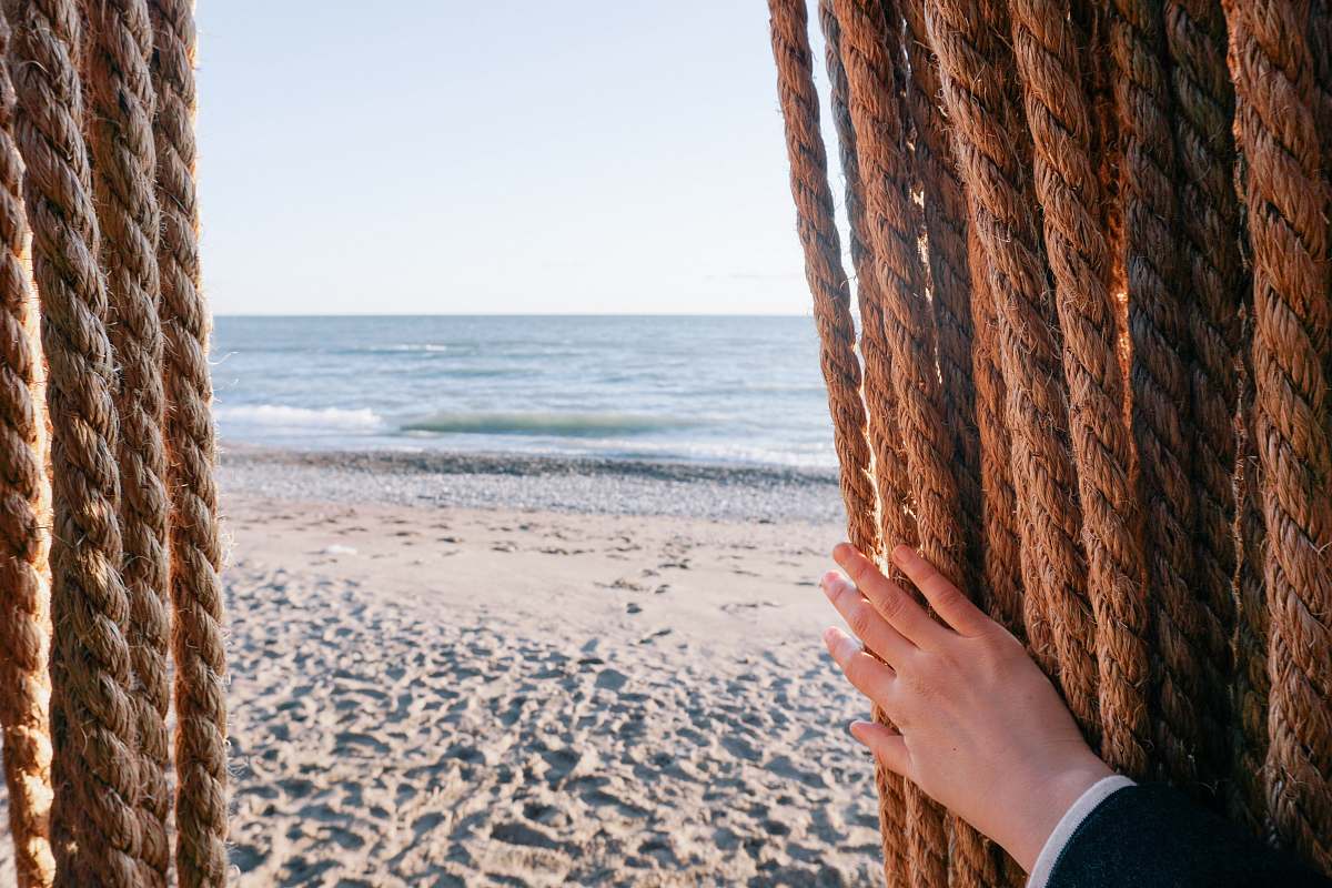 sea person holding brown rope over seeing body of water shore