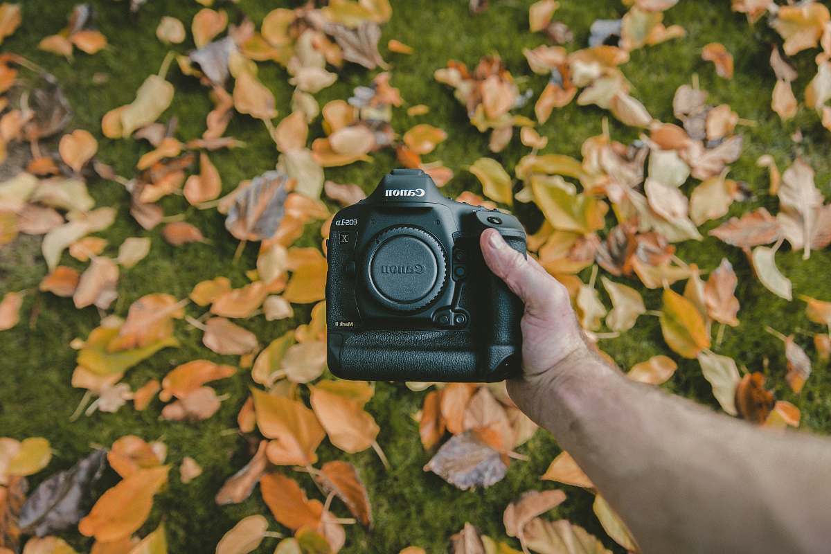 camera person holding Canon DSLR camera lens cap