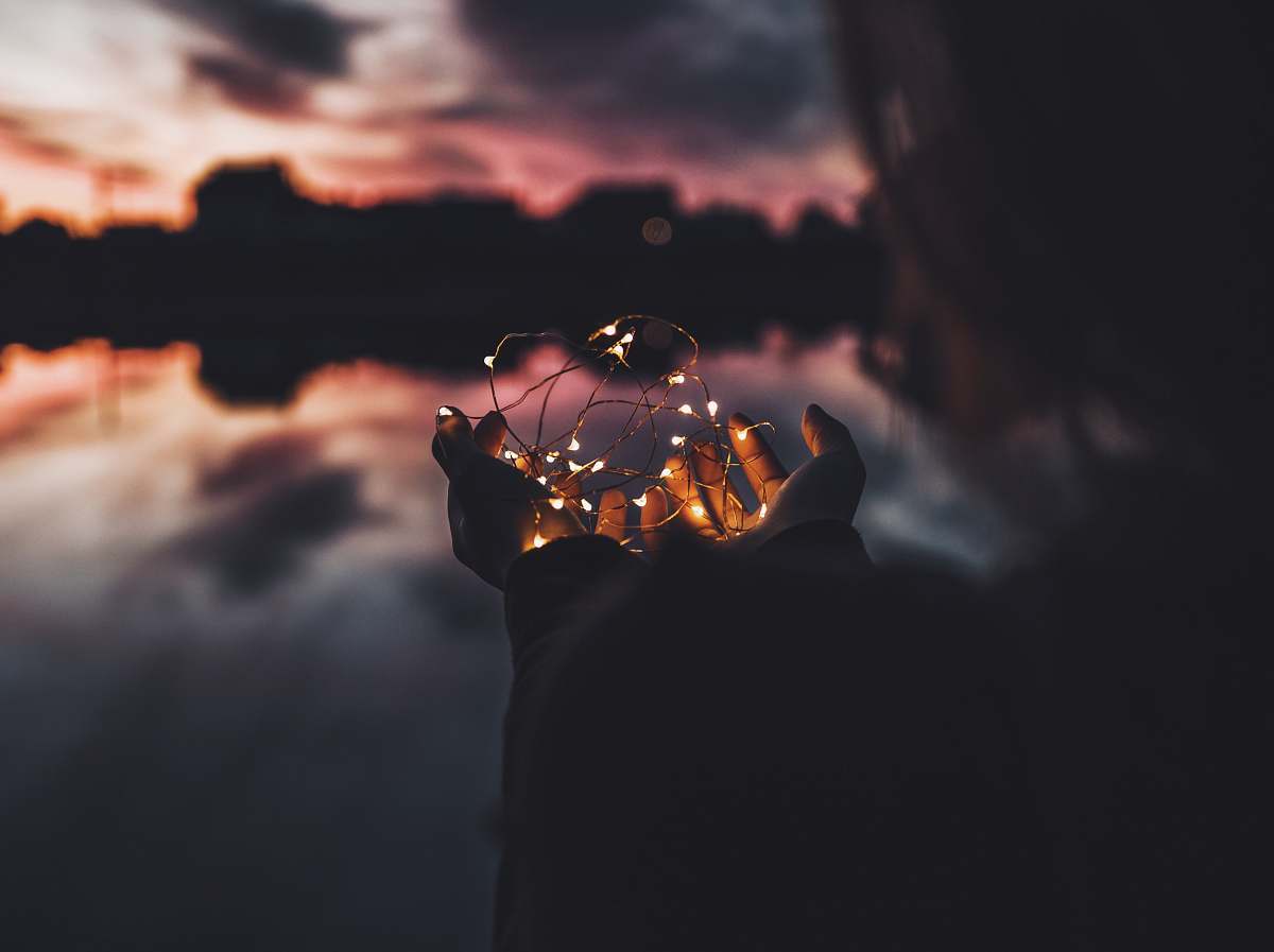 light person holding turned on string lights during nighttime night