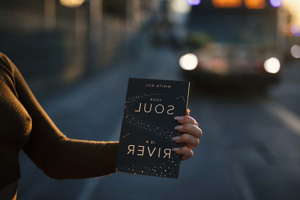 holding person holding Your Soul is a River book book