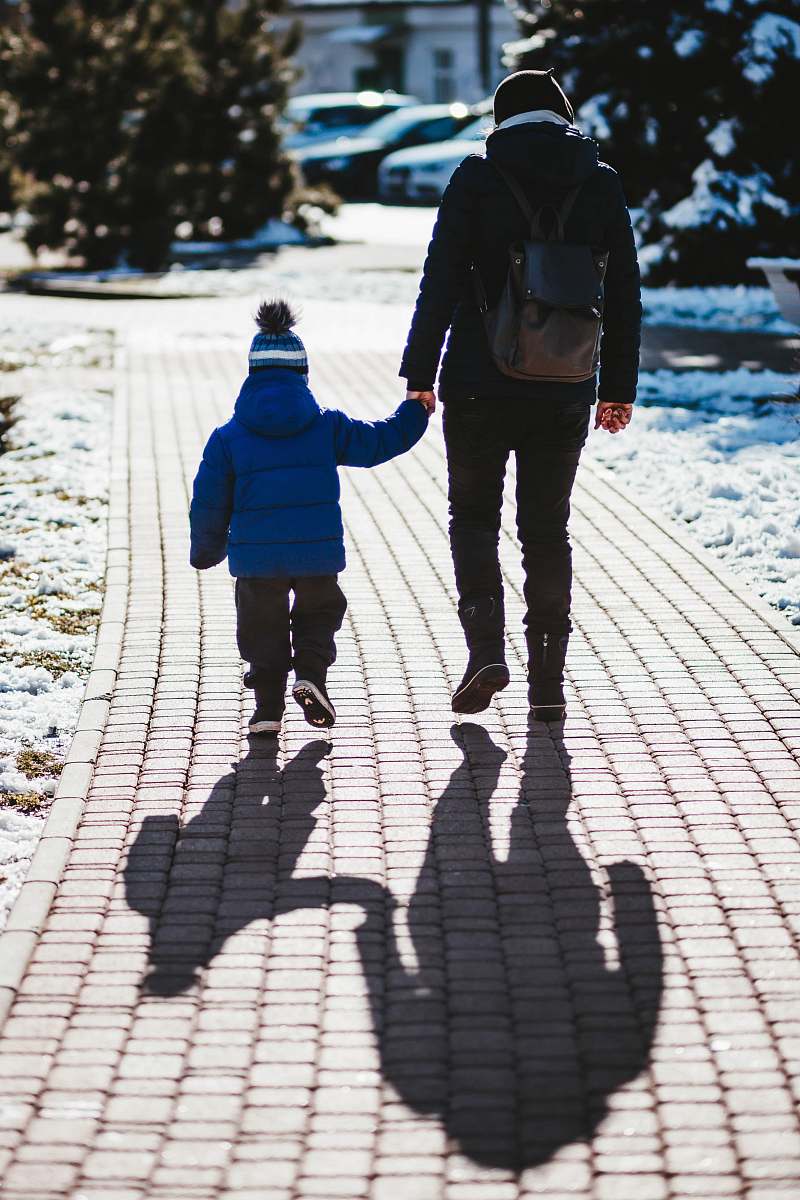 person person in black jacket holding hand with toddler holding hands