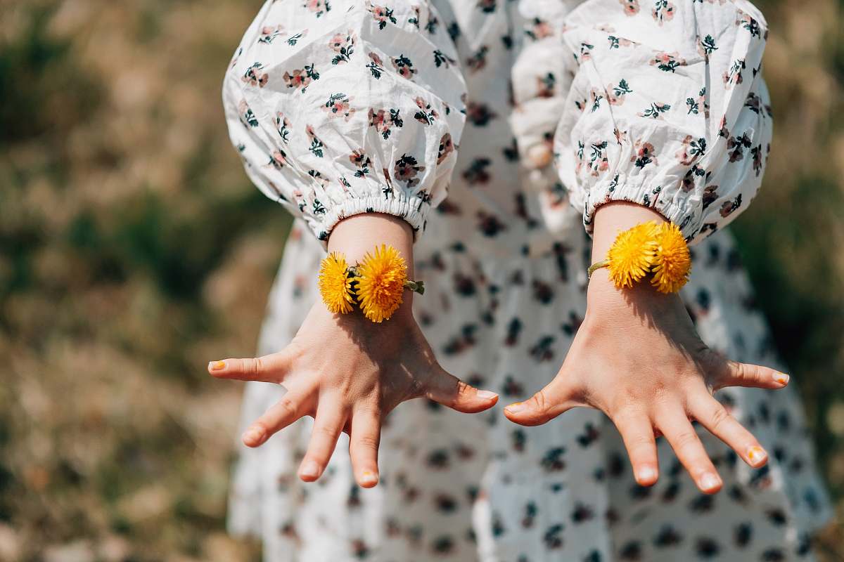 finger person showing orange petaled flower bracelet flower