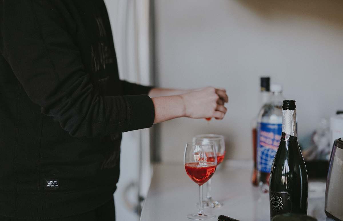 wrist person standing beside two wine glasses bottle