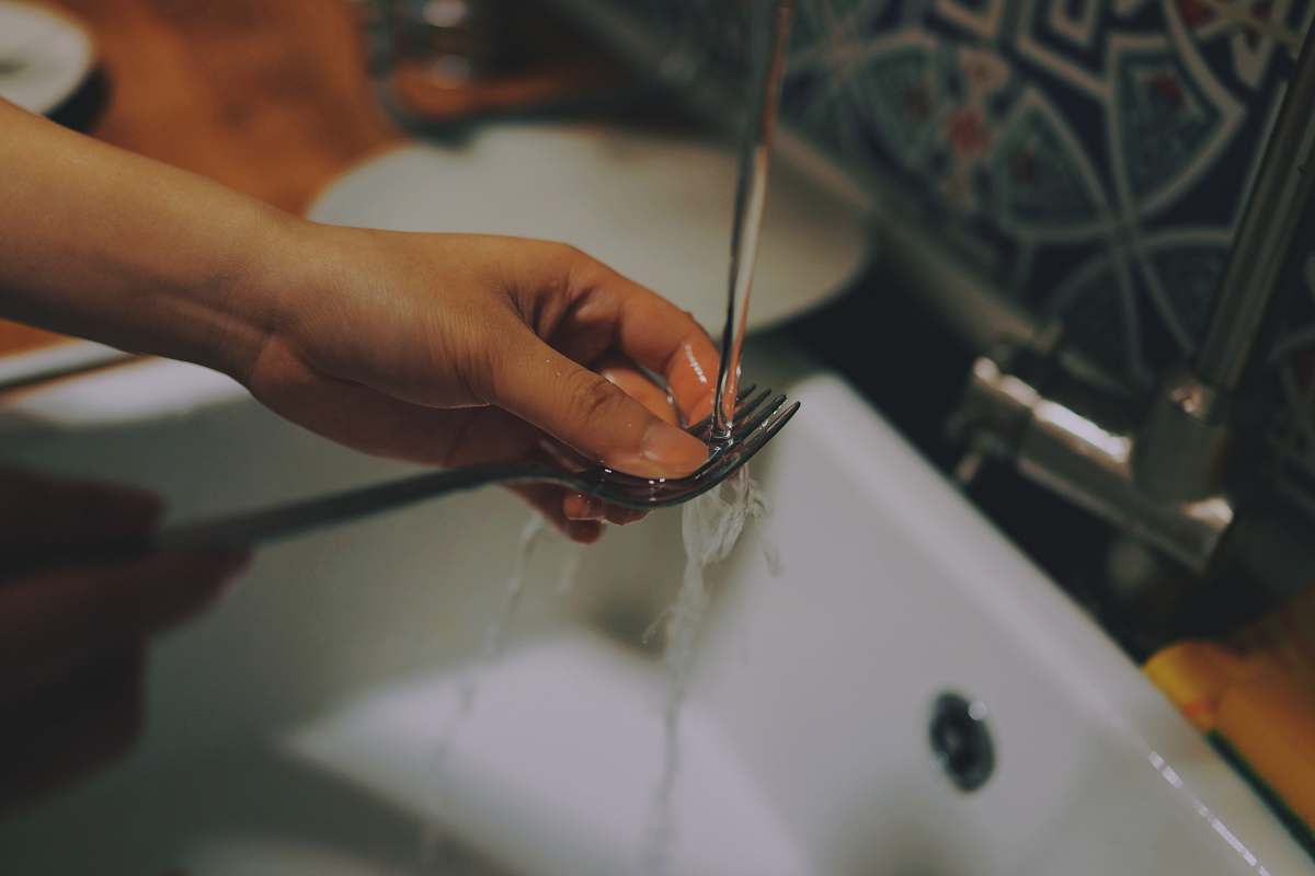 water person washing fork tap