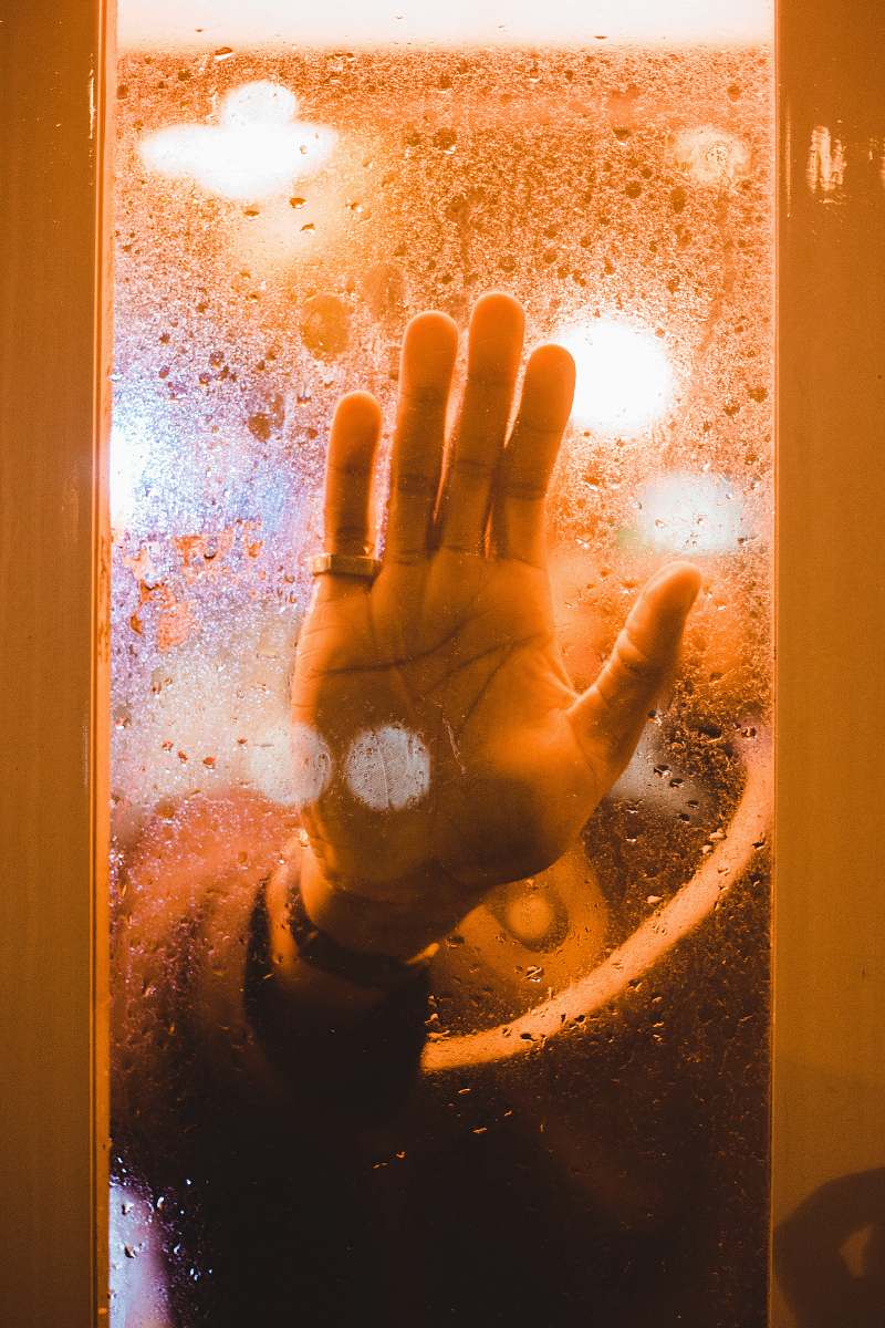 flare person's hand touching a clear glass pane light