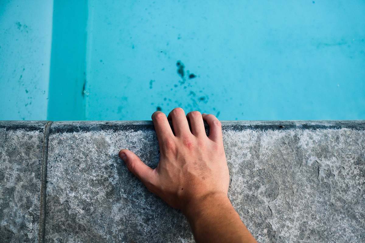pool person's left hand holding gray concrete surface caucasian