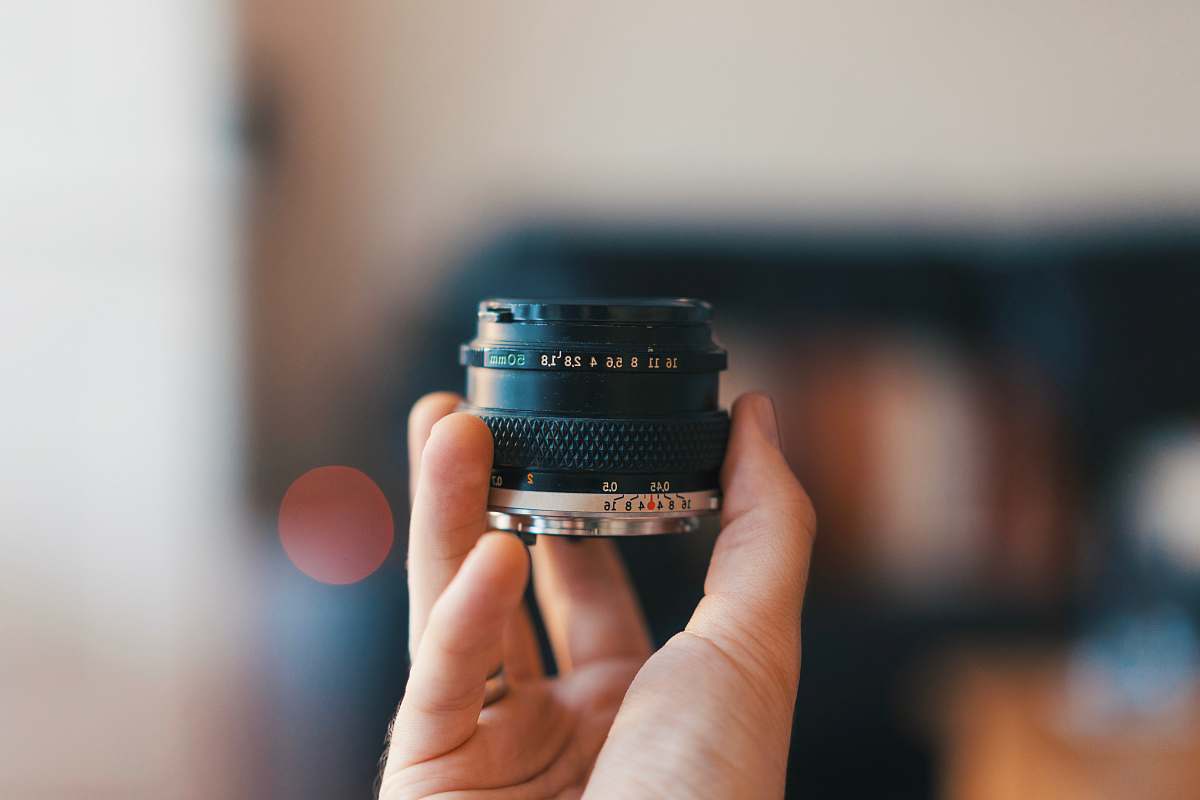camera selective focus photography of person holding camera lens electronics