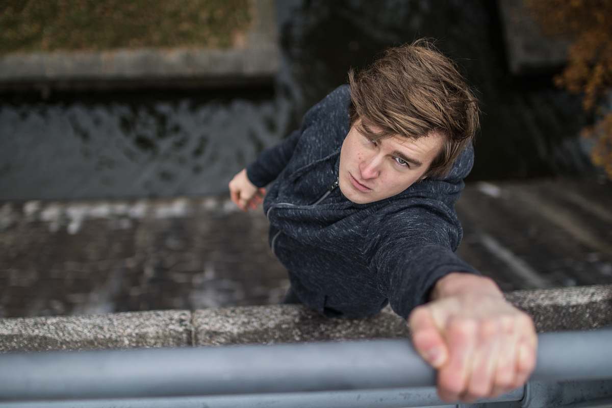 person shallow focus photo of man holding on gray steel rail human