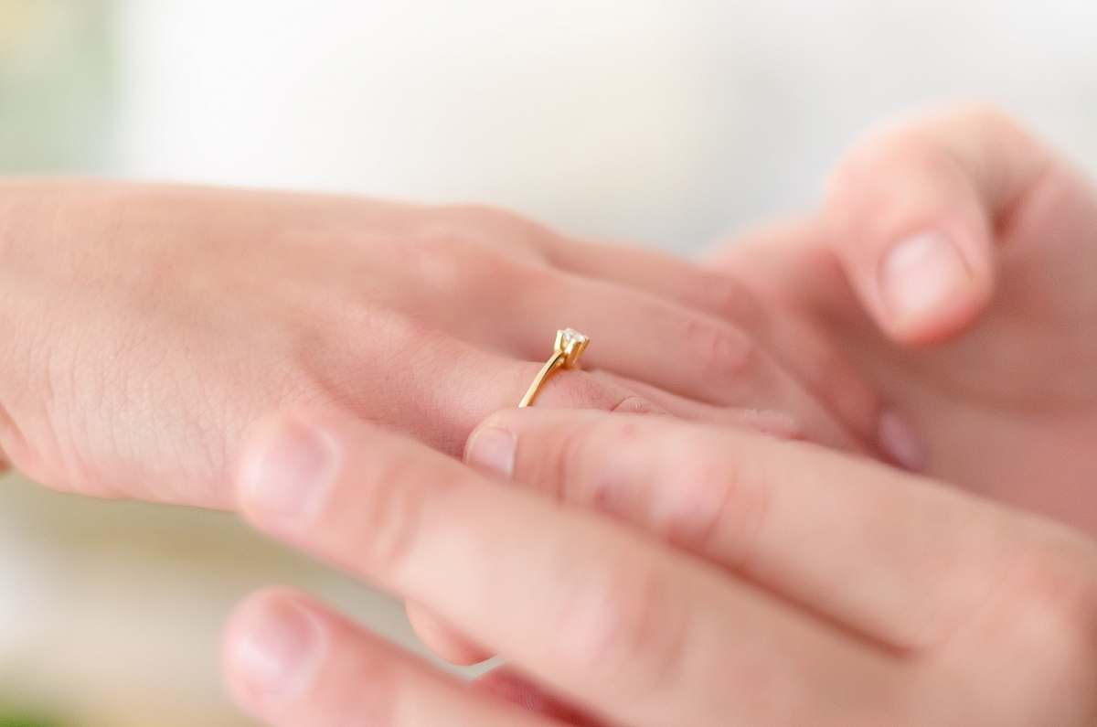 finger shallow focus photo of person putting gold-colored ring ring