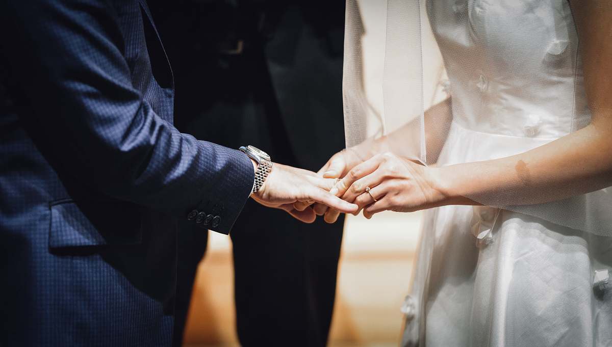 person woman inserting ring on man's finger holding hands