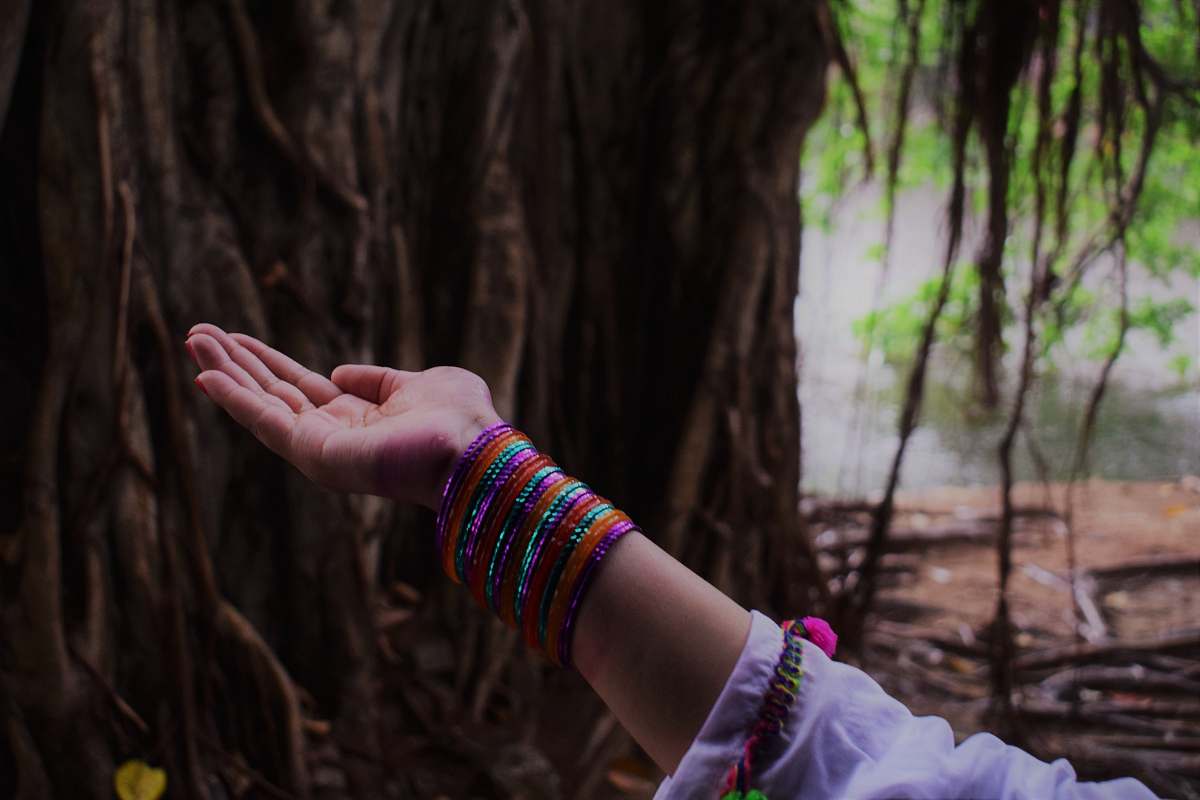 tree woman raising her hand upward opening her palm bangles