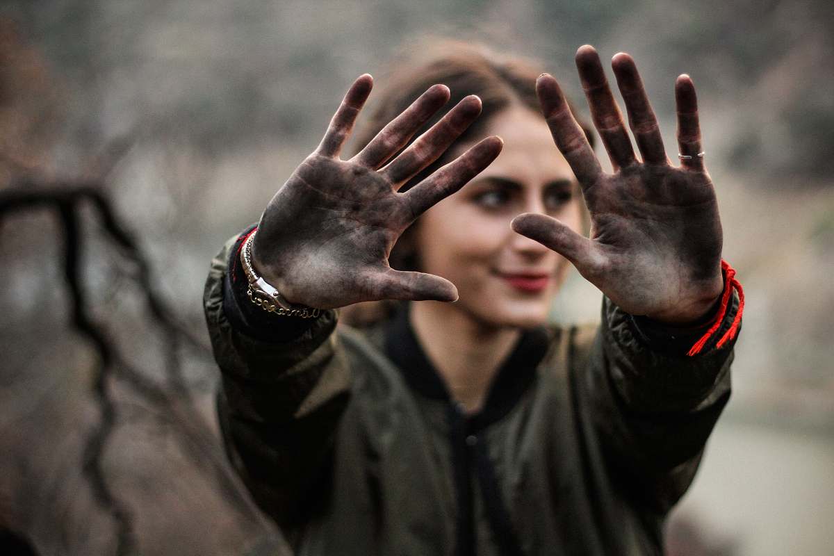 person woman showing her hands with black paint people