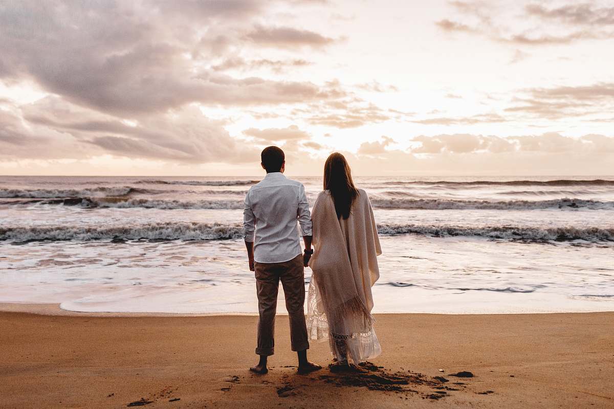 person woman wearing beige dress and man wearing white dress shirt standing on seashore human