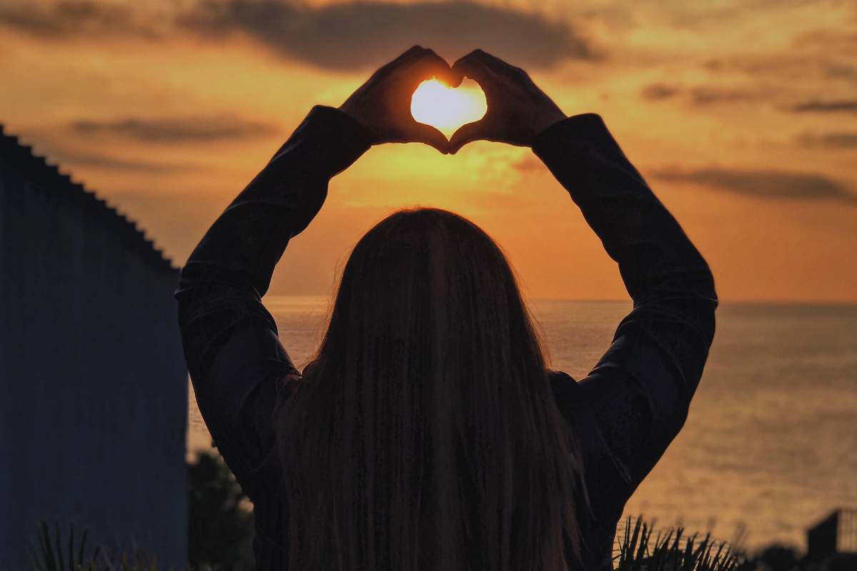 person woman with hands in heart shape at sunset human