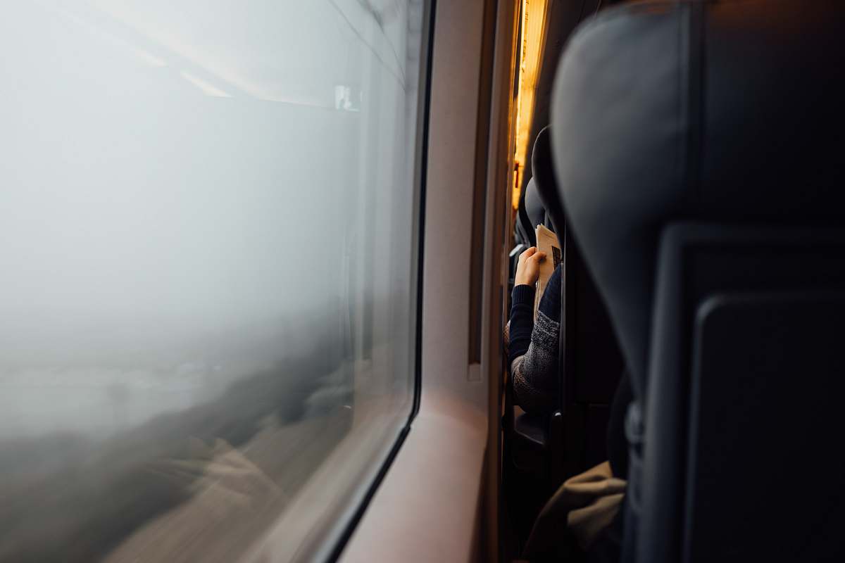 window Person reading newspaper from behind with headrest in foreground near train carriage window train