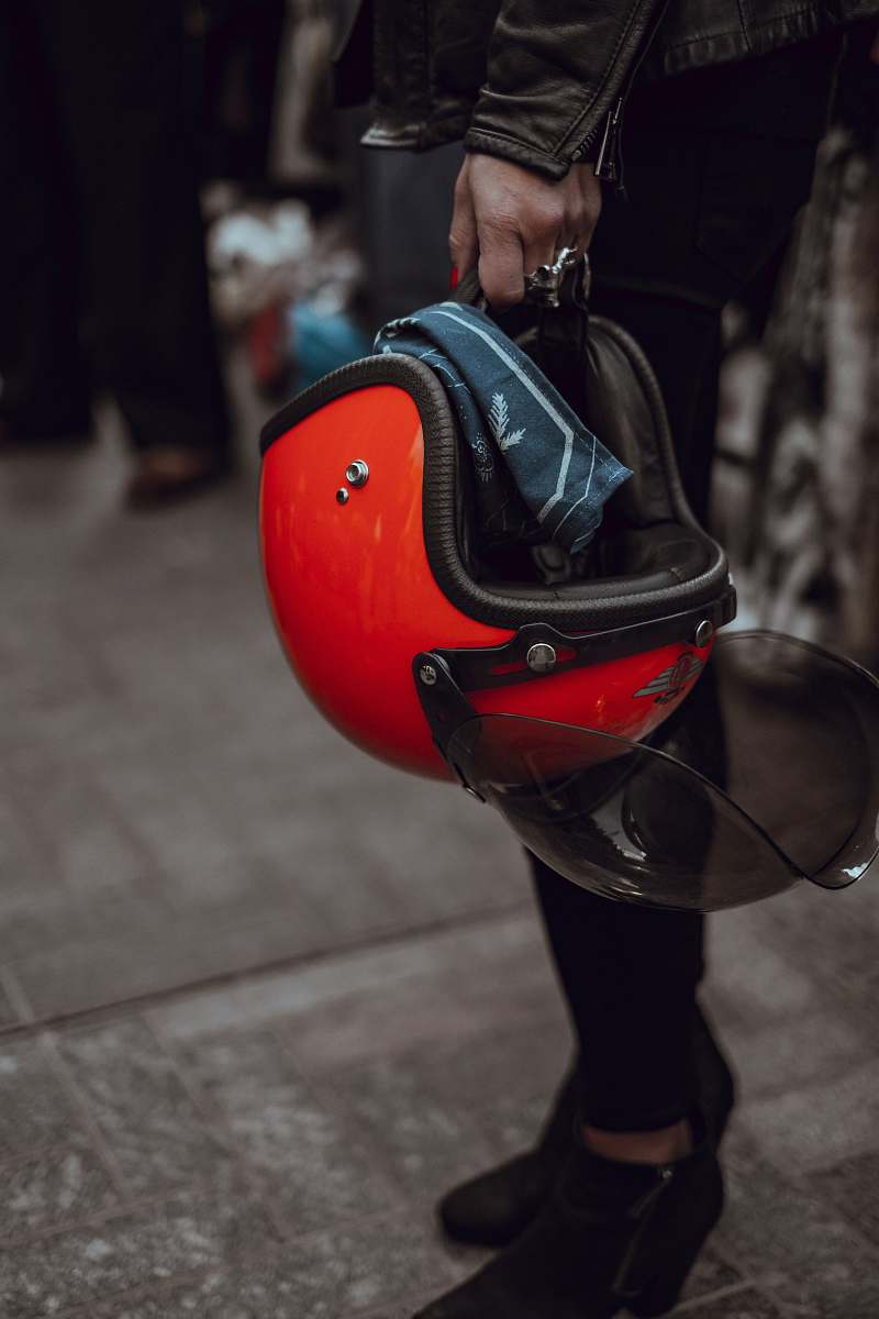 red person holding red half-face helme carrying helmet